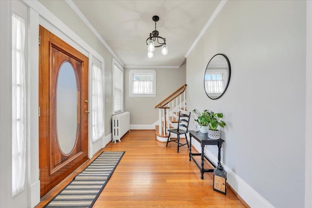 foyer entrance featuring baseboards, radiator, light wood-style flooring, stairway, and ornamental molding