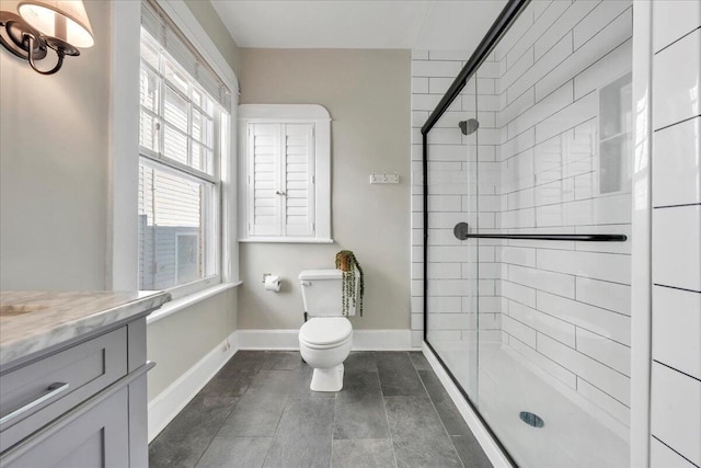 bathroom with a stall shower, toilet, vanity, and baseboards