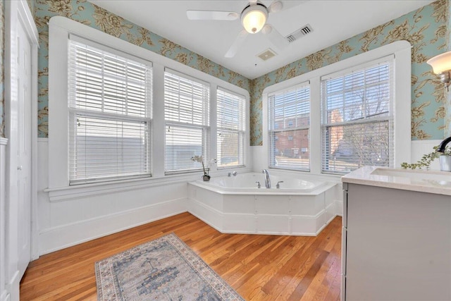 full bathroom with a garden tub, wood finished floors, vanity, visible vents, and wallpapered walls