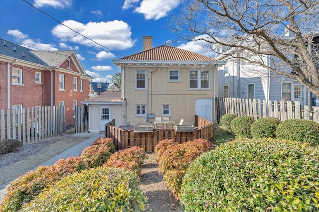 rear view of property featuring brick siding, fence, and a chimney