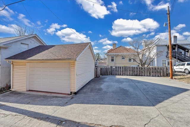 view of side of property with a garage, a shingled roof, and fence