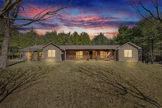 single story home featuring brick siding, covered porch, and a front lawn