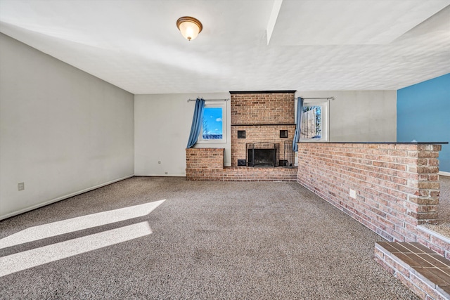 unfurnished living room with brick wall, baseboards, a brick fireplace, and carpet