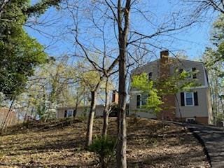 view of home's exterior featuring a gambrel roof and a chimney