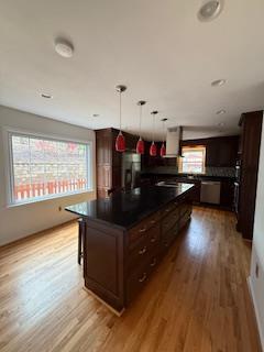 kitchen with white cabinets, light wood finished floors, a sink, backsplash, and light stone countertops
