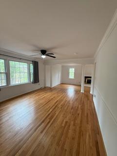 unfurnished living room featuring wood finished floors, a healthy amount of sunlight, and ornamental molding