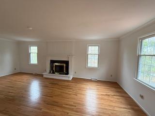 unfurnished living room with ornamental molding, a healthy amount of sunlight, and wood finished floors