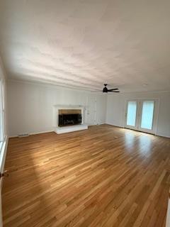 unfurnished living room with wood finished floors and a fireplace with raised hearth