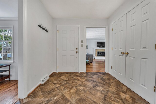 entrance foyer featuring baseboards, visible vents, and a fireplace with raised hearth