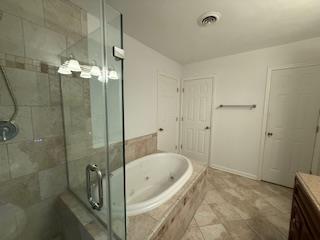 bathroom with a tub with jets, vanity, baseboards, visible vents, and a stall shower