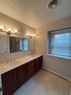 spare room with wood finished floors, a healthy amount of sunlight, a ceiling fan, and visible vents