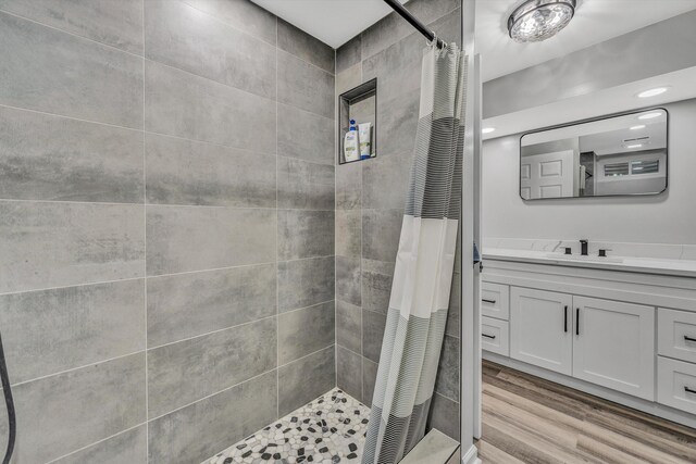 bathroom with wood finished floors, vanity, and tiled shower