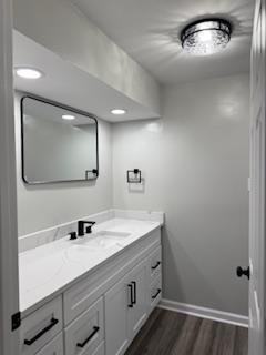 basement featuring baseboards, a fireplace with raised hearth, and recessed lighting