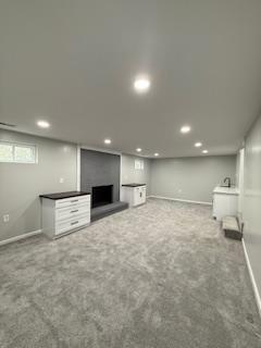 basement with recessed lighting, carpet, and a fireplace with raised hearth