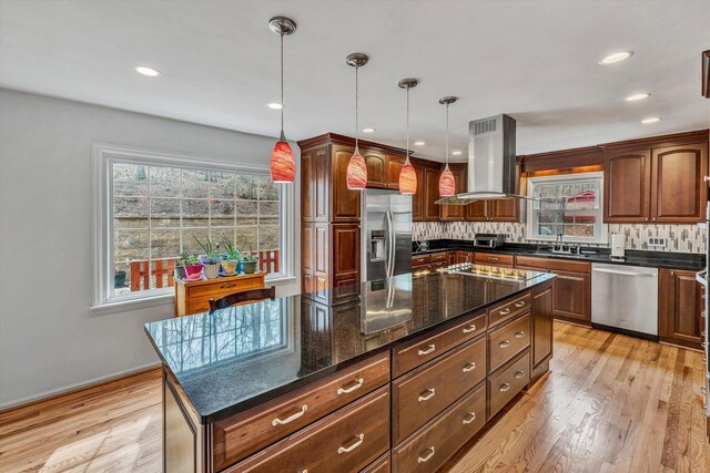 kitchen featuring hanging light fixtures, island range hood, appliances with stainless steel finishes, and plenty of natural light