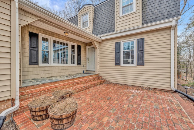 view of exterior entry with a shingled roof