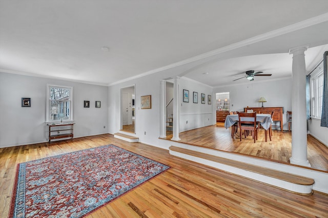 living area with ornate columns, hardwood / wood-style flooring, crown molding, and a ceiling fan