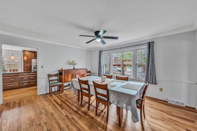 dining space with ornamental molding, visible vents, ceiling fan, and light wood-type flooring