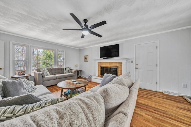 living area with visible vents, a ceiling fan, light wood finished floors, and crown molding