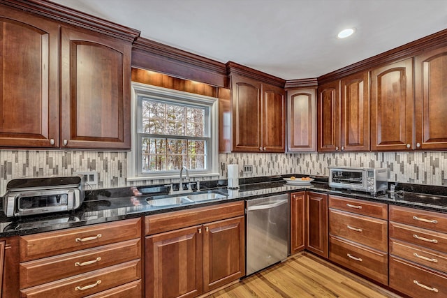 kitchen featuring dark stone countertops, decorative backsplash, a toaster, dishwasher, and a sink