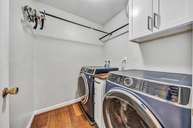 laundry room with wood finished floors, separate washer and dryer, cabinet space, and baseboards