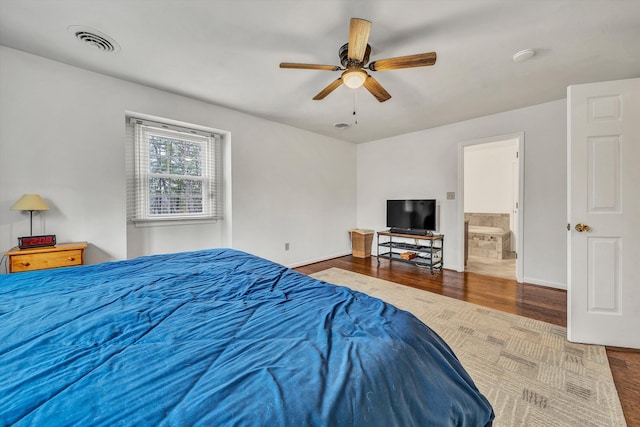 bedroom featuring ensuite bathroom, visible vents, wood finished floors, and baseboards