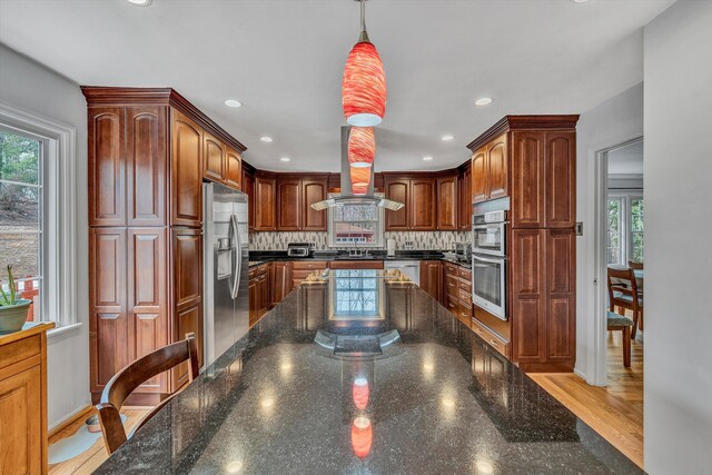 kitchen featuring light wood-type flooring, dark countertops, island range hood, black electric stovetop, and double oven