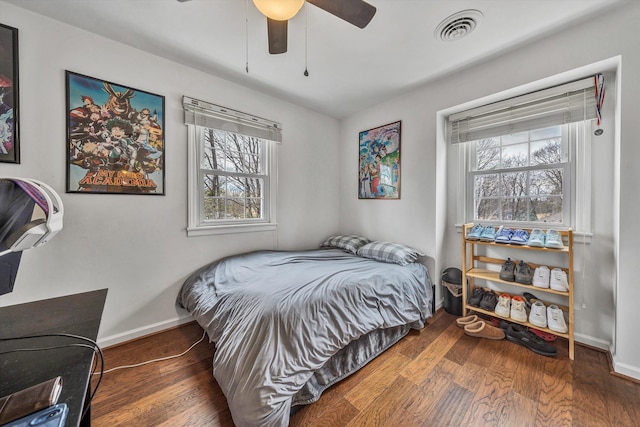 bedroom with baseboards, visible vents, wood finished floors, and multiple windows