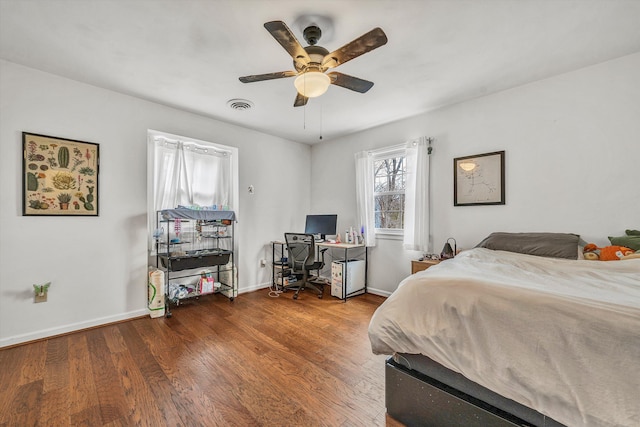 bedroom featuring wood finished floors, visible vents, a ceiling fan, and baseboards