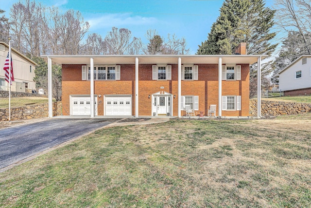 raised ranch featuring a garage, driveway, brick siding, and a chimney