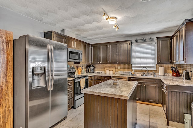 kitchen with light tile patterned flooring, stainless steel appliances, a sink, dark brown cabinets, and decorative backsplash