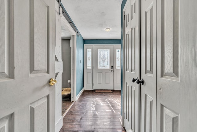 entryway featuring a barn door, baseboards, and wood finished floors