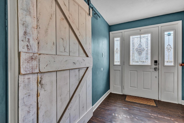 entrance foyer with a barn door, baseboards, and wood finished floors