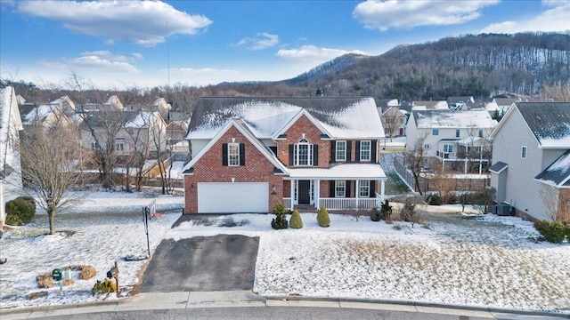 traditional-style house featuring aphalt driveway, brick siding, covered porch, central AC, and a mountain view