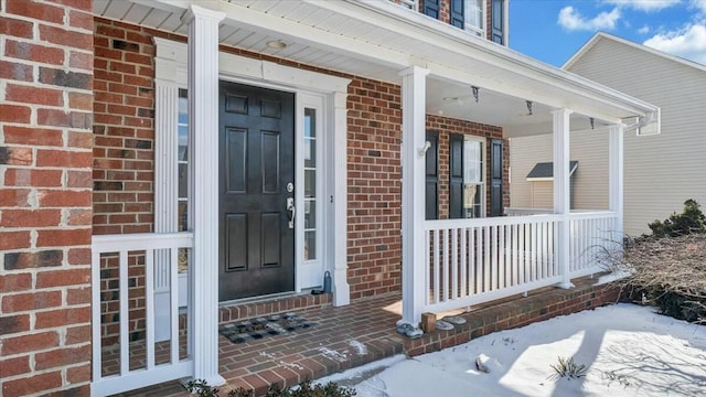 snow covered property entrance featuring brick siding