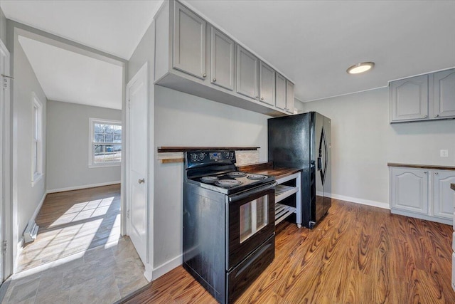 kitchen with baseboards, black appliances, wood finished floors, and gray cabinetry