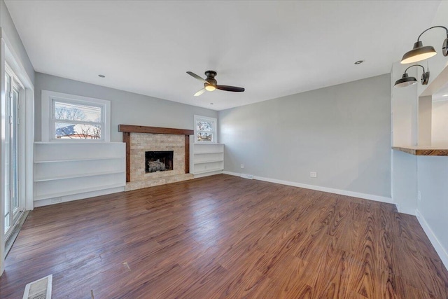 unfurnished living room featuring dark wood-style flooring, visible vents, plenty of natural light, and baseboards