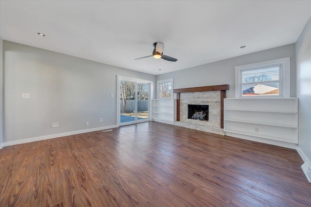 unfurnished living room featuring baseboards, wood finished floors, and a healthy amount of sunlight