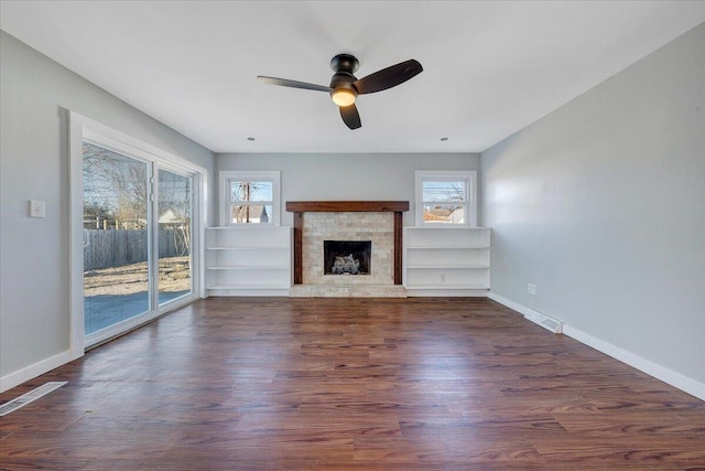 unfurnished living room with dark wood-style floors, a fireplace, a ceiling fan, and baseboards