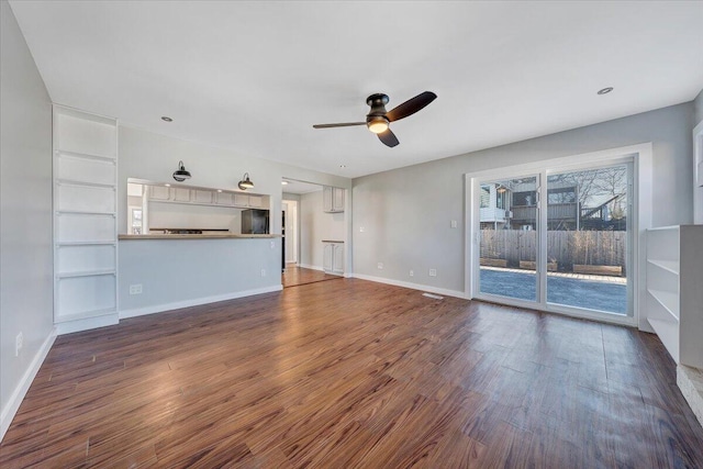 unfurnished living room with dark wood-style flooring, ceiling fan, and baseboards