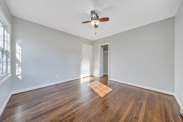 spare room with dark wood-style floors, ceiling fan, and baseboards