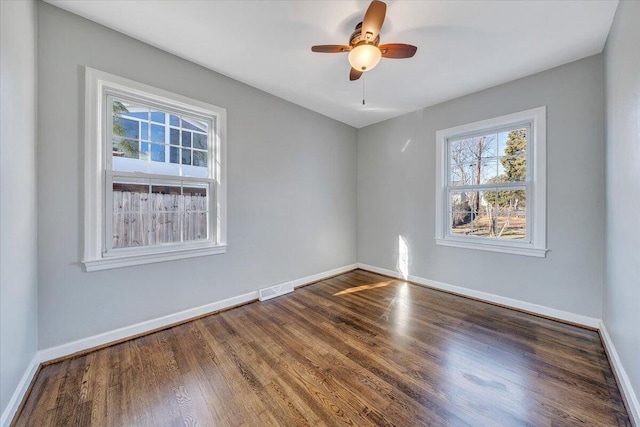 spare room with visible vents, dark wood finished floors, baseboards, and ceiling fan