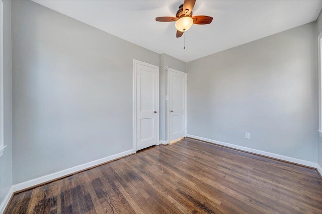 spare room featuring ceiling fan, baseboards, and dark wood-style flooring