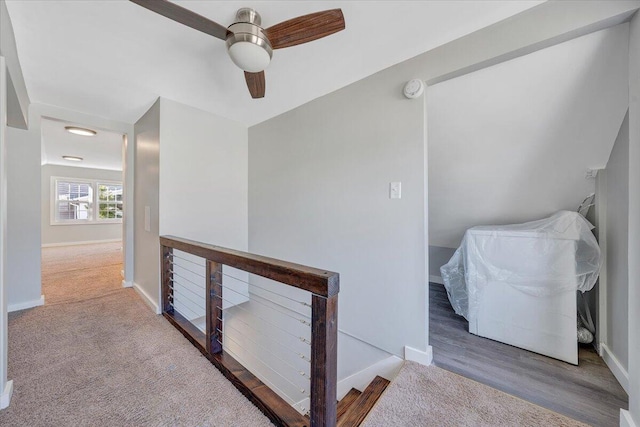 hallway with baseboards, an upstairs landing, and wood finished floors