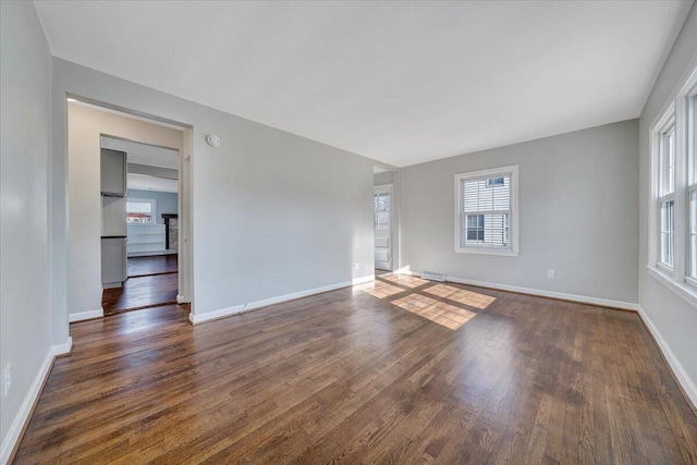 unfurnished room featuring dark wood-type flooring and baseboards