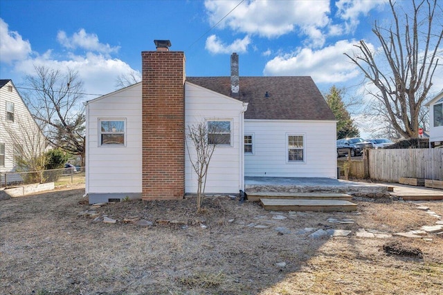 rear view of house with roof with shingles, fence, a chimney, and a patio