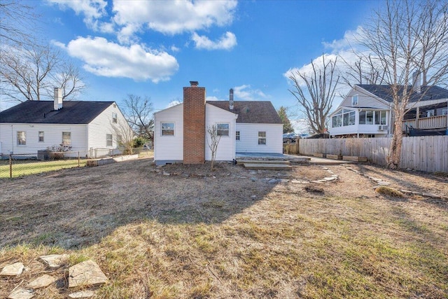 rear view of property with a fenced backyard, a chimney, and a lawn