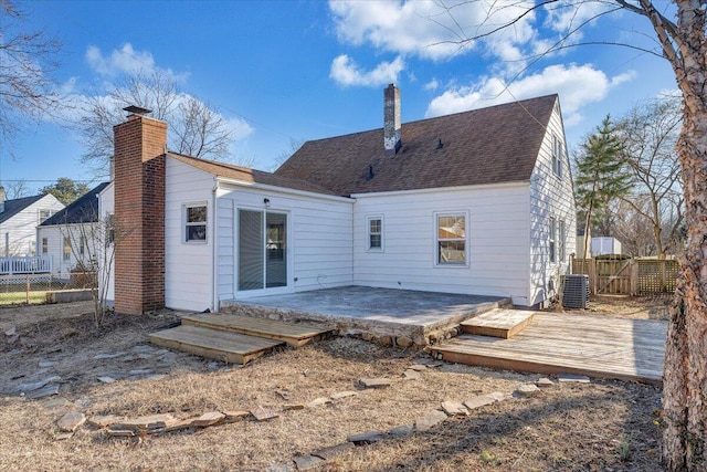 rear view of property featuring a deck, a chimney, cooling unit, and fence