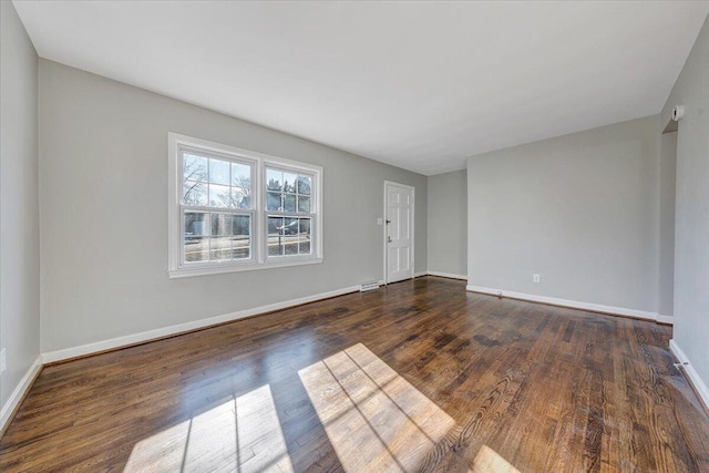 empty room featuring dark wood-type flooring and baseboards