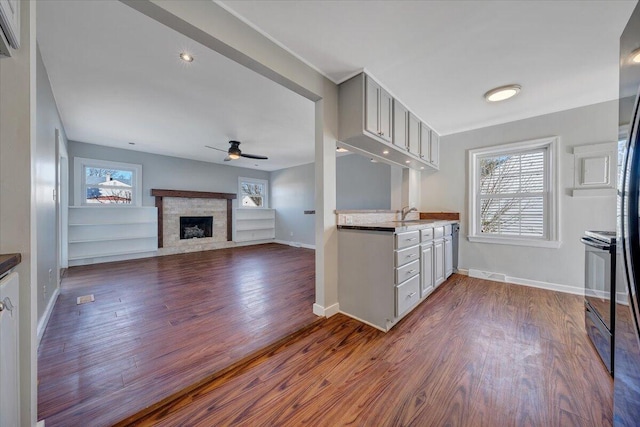 kitchen with a fireplace with flush hearth, open floor plan, a healthy amount of sunlight, and electric range oven